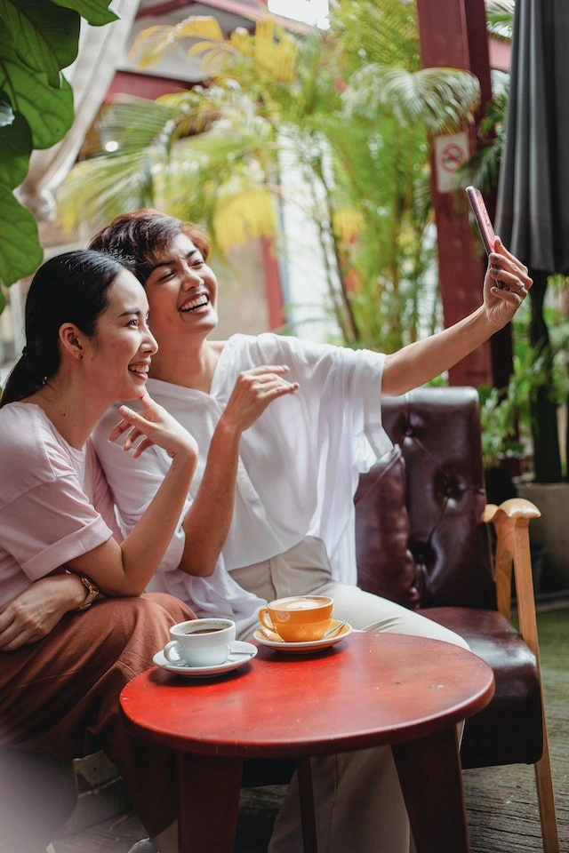 Two friends having fun and taking selfies in the cafe
